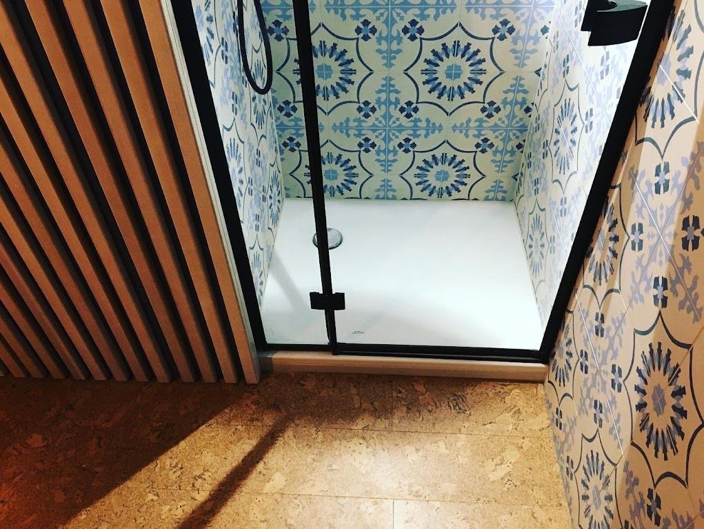 Blue patterned tiles in a shower room with timber slats