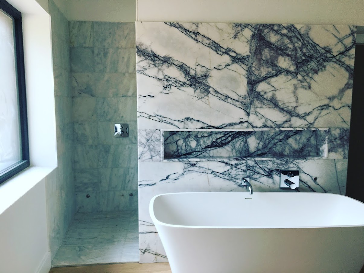 Natural stone tiled wall beside a freestanding bath